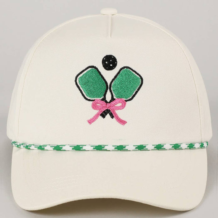 Beige cap with pickleball-themed design featuring green rackets, pink bow, and black ball 