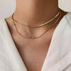 Gold necklaces on a person wearing a white top 