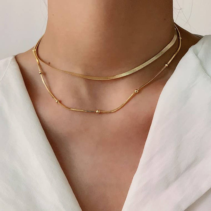 Gold necklaces on a person wearing a white top 