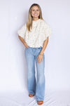 Woman wearing a white blouse with ruffled sleeves and blue jeans 