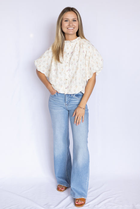 Woman wearing a white blouse with ruffled sleeves and blue jeans 