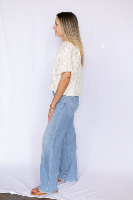 Woman wearing a white floral blouse and blue jeans 