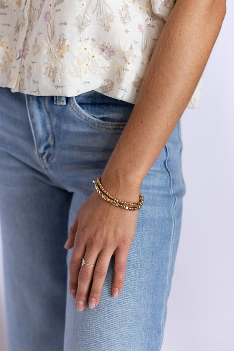 Person wearing a floral top, blue jeans, and gold bracelet