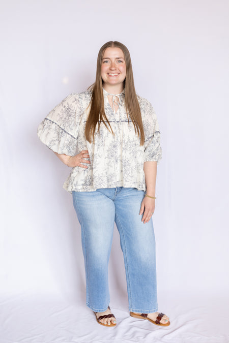 Woman wearing a floral blouse and blue jeans 