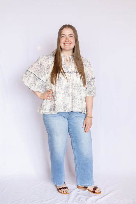 Woman wearing a floral blouse and blue jeans 
