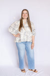 Woman wearing a floral blouse and blue jeans 