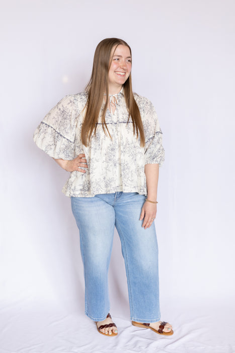 Woman wearing a floral blouse and blue jeans 