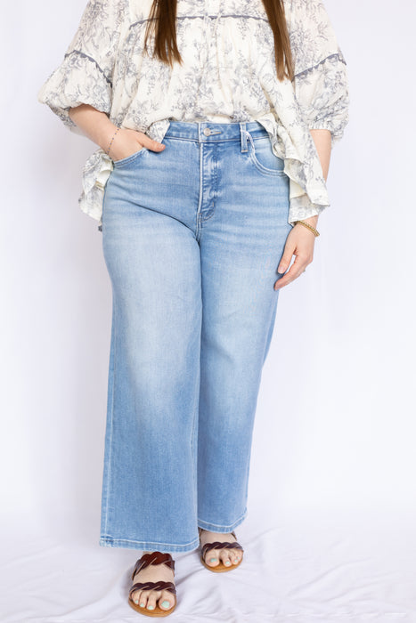 Woman wearing light blue jeans and a patterned top 