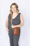 Woman wearing a gray jumpsuit with a brown crossbody bag 