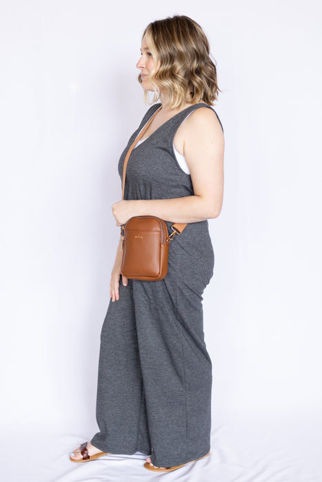 Woman wearing a gray jumpsuit with a brown leather bag