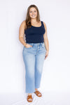 Woman wearing a navy tank top and light blue jeans 