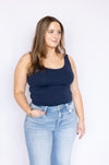 Woman wearing a navy tank top and light blue jeans 