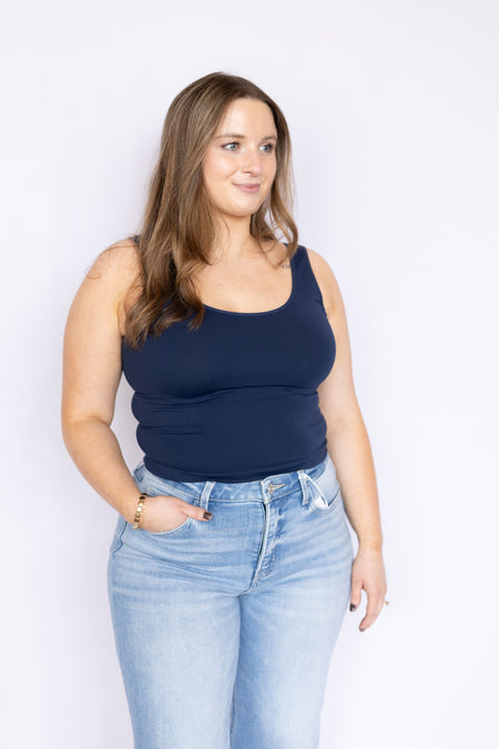 Woman wearing a navy tank top and light blue jeans 