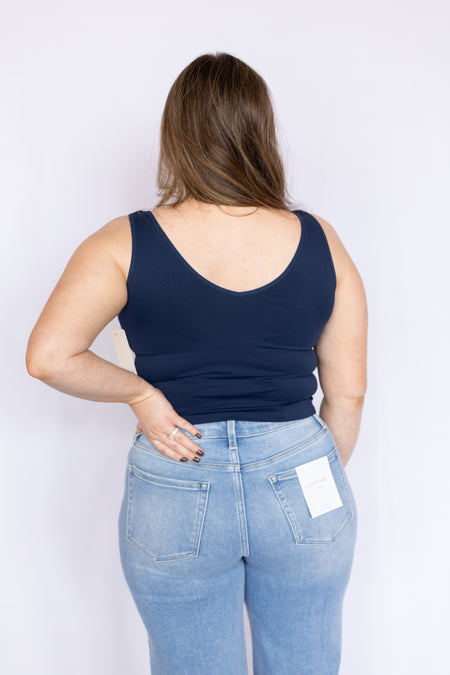 Person wearing a navy tank top and light blue jeans