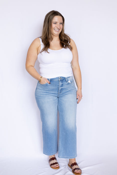 Woman wearing a white tank top and blue jeans 