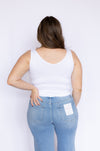 Woman wearing a white tank top and blue jeans 