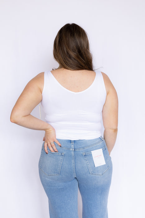 Woman wearing a white tank top and blue jeans 