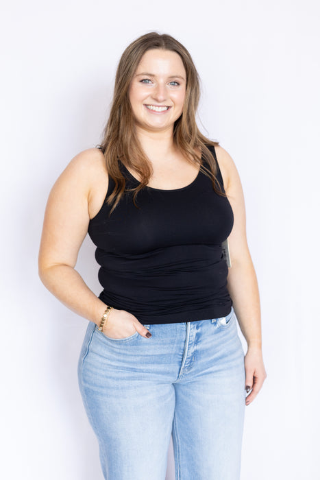 Woman wearing a black tank top and light blue jeans 