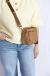 Person wearing a beige crossbody bag 