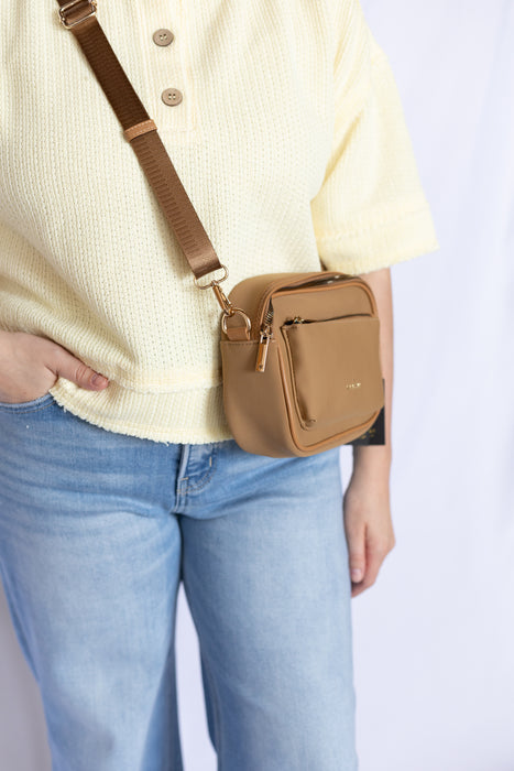 Person wearing a beige crossbody bag 