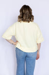 Person wearing a light yellow shirt and blue jeans