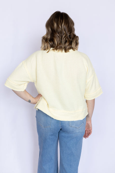 Person wearing a light yellow shirt and blue jeans