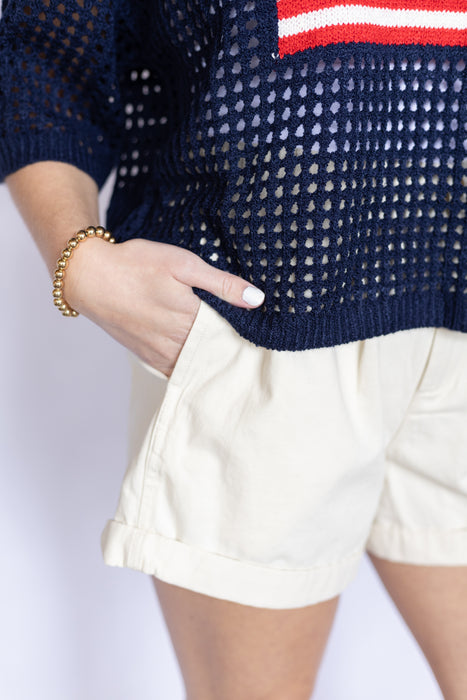 Navy sweater with red and white stripe and beige shorts 