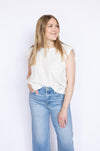 Woman wearing a white sleeveless top and blue jeans 