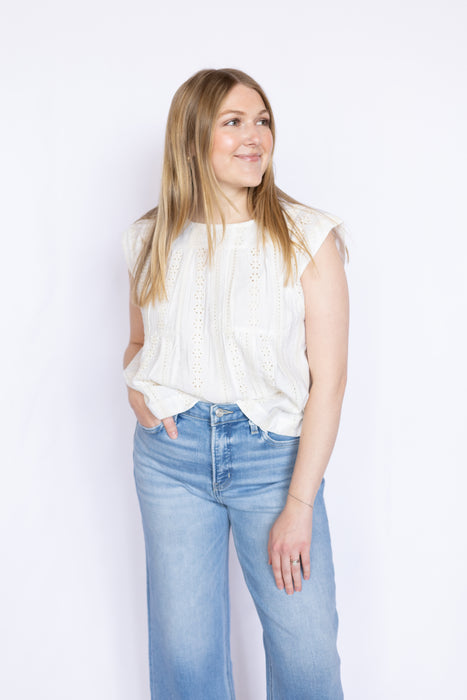 Woman wearing a white sleeveless top and blue jeans 