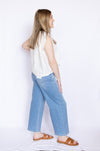 Woman wearing a white sleeveless top and blue jeans 