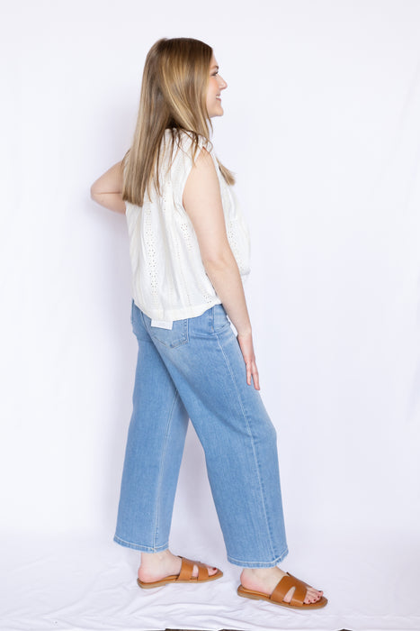 Woman wearing a white sleeveless top and blue jeans 