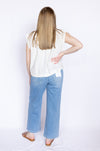 Person wearing a white sleeveless top and blue jeans 
