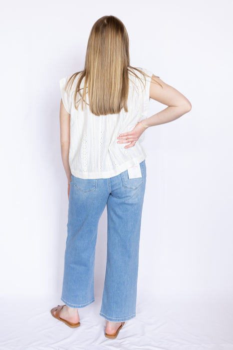Person wearing a white sleeveless top and blue jeans 