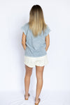 Woman wearing a light blue top and white shorts 