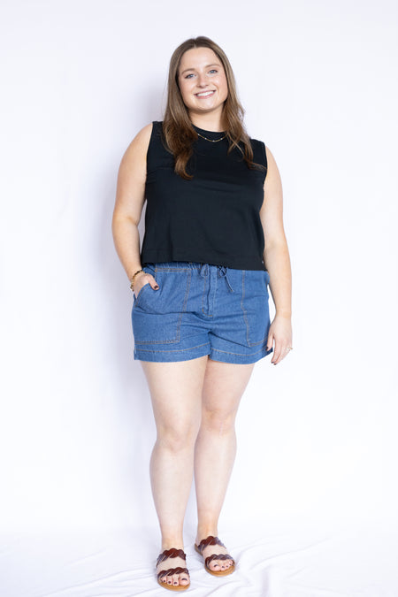 Woman wearing a black sleeveless top and blue shorts 