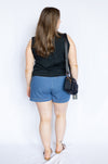 Woman wearing a black sleeveless top and blue shorts