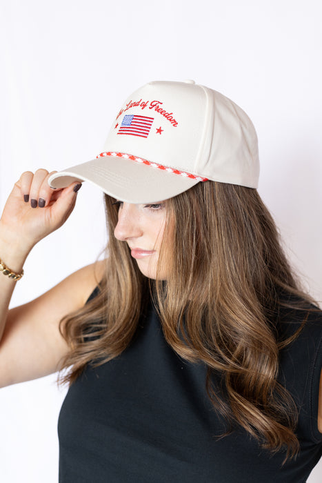 Woman wearing a beige cap with red and white text and an American flag hat