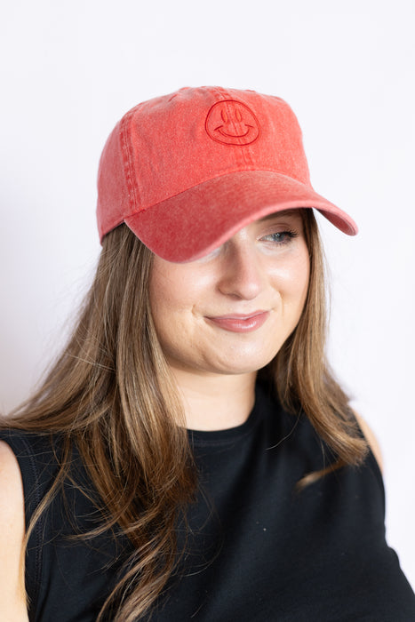 Woman wearing a red cap with a smiley face design