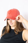 Woman wearing a red cap with a smiley face design