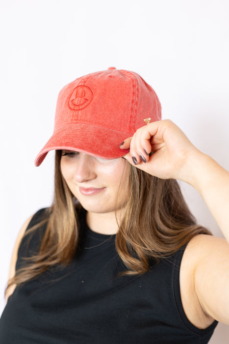 Woman wearing a red cap with a smiley face design