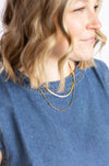 Woman wearing a gold necklace with a blue shirt 