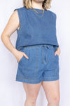 Person wearing a blue denim sleeveless top and shorts 