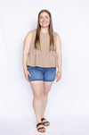 Woman wearing a beige checkered top and blue shorts 