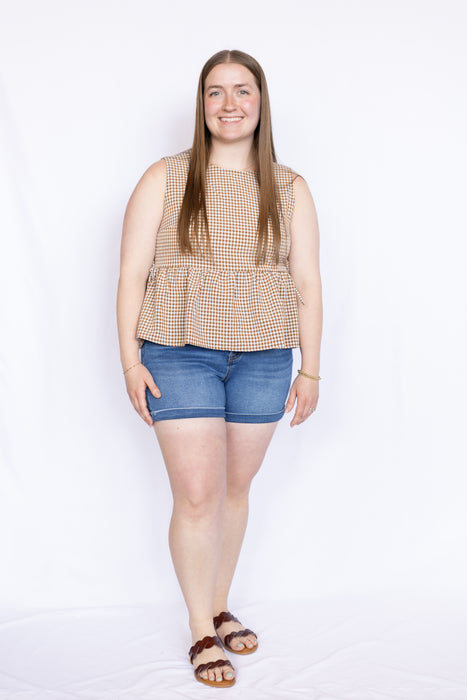 Woman wearing a beige checkered top and blue shorts 