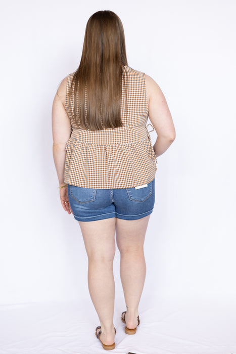 Woman wearing a sleeveless checkered top and denim shorts 