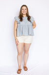 light blue ruffle babydoll blouse with white high waisted shorts and brown open sandals
