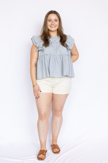 light blue ruffle babydoll blouse with white high waisted shorts and brown open sandals