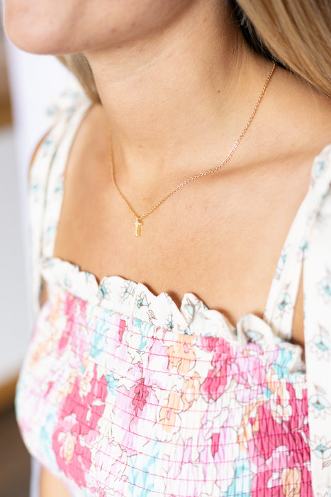 Close-up of a person wearing a floral top and gold cross necklace.