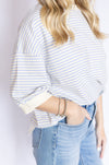 Person wearing a light blue and white striped shirt and blue jeans 