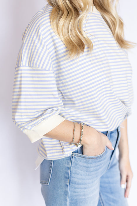 Person wearing a light blue and white striped shirt and blue jeans 